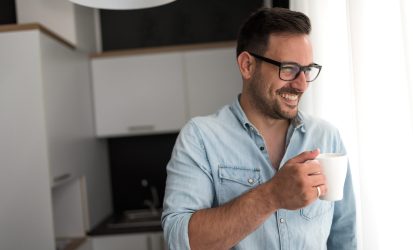 Handsome man having cup of coffee at home in the morning