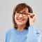 vision and old people concept - portrait of smiling senior woman in glasses over grey background